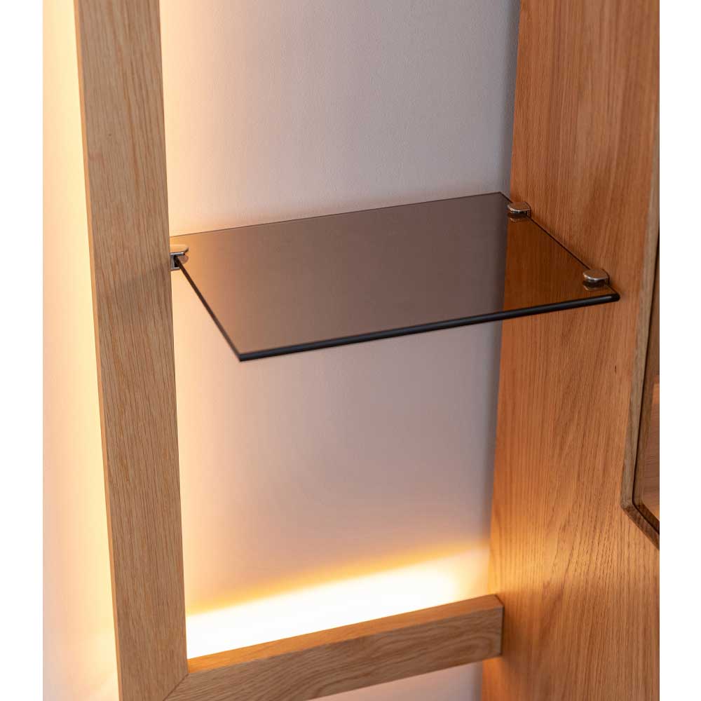 Einzelnes Glasregal mit LED-Beleuchtung in einer modernen Hängevitrine aus hellem Holz – Cocondar