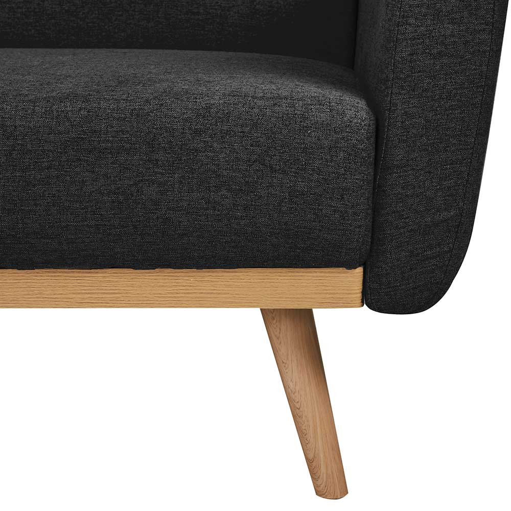 Detailansicht der schrägen Holzfüße und des dunkelgrauen Stoffbezugs des Sofas – Adamu