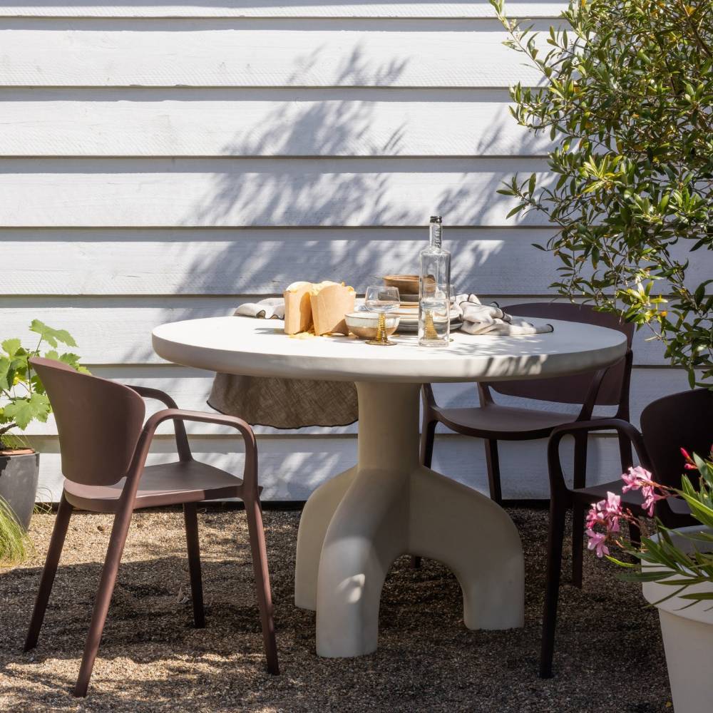 Mehrere braune stapelbare Gartenstühle um einen Esstisch im Freien platziert – Dalfonso