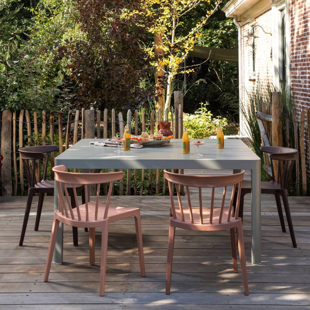 Zwei lachsfarbene stapelbare Outdoorstühle am Gartentisch im 2er Set mit braunen Stühlen – Ionesa