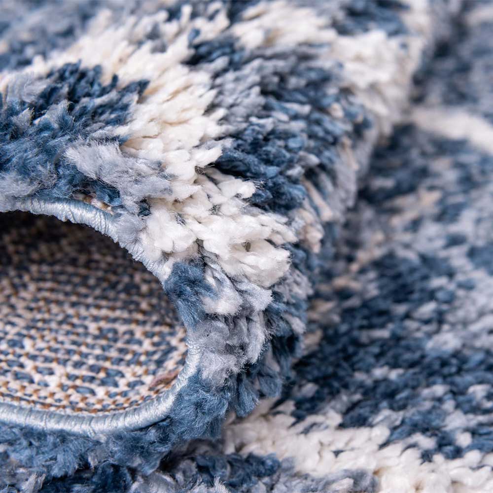 Gerollter Teppichläufer in Blau und Creme zeigt die dichte Shaggy Textur und die Unterseite – Addagio