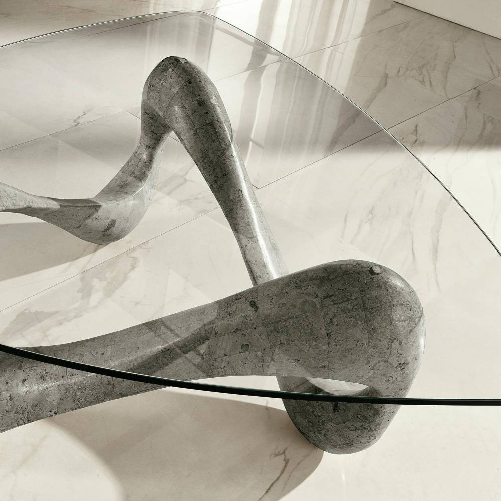 Moderner Wohnzimmertisch aus grauem Stein mit transparenter Glasplatte auf Fliesen – Same