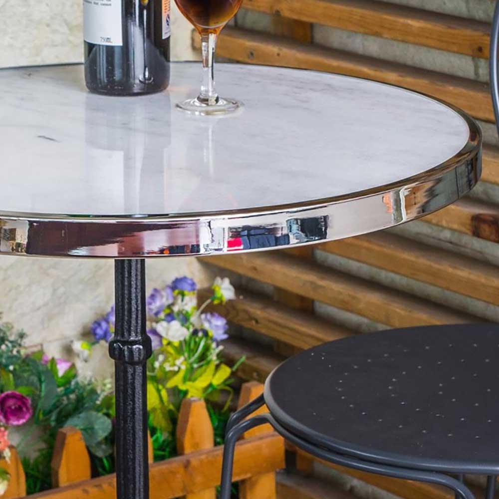 Eleganter runder Marmortisch mit Chromrand und schwarzem Stuhl für einen Cafébereich – Perleberg