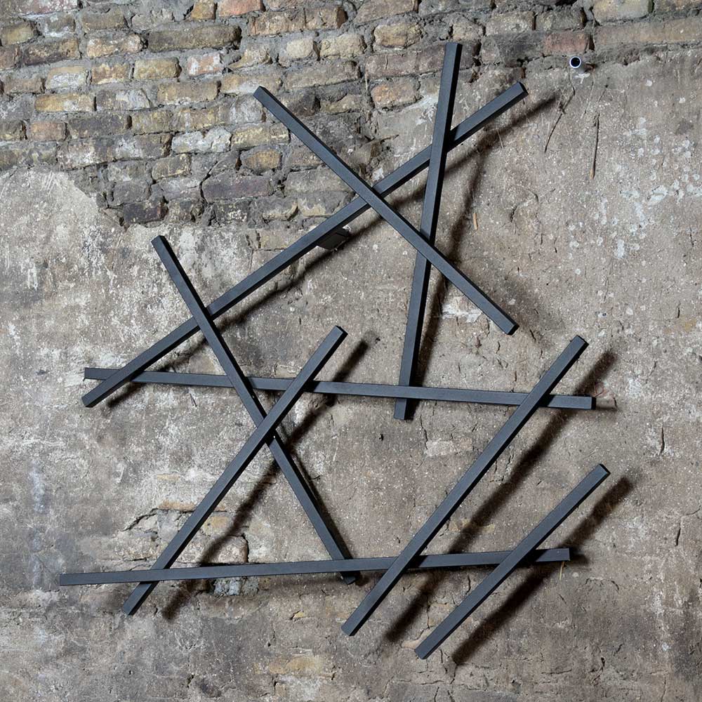 Moderne Wandgarderobe aus schwarzen Metallstreben an rustikaler Ziegelwand – Volkma