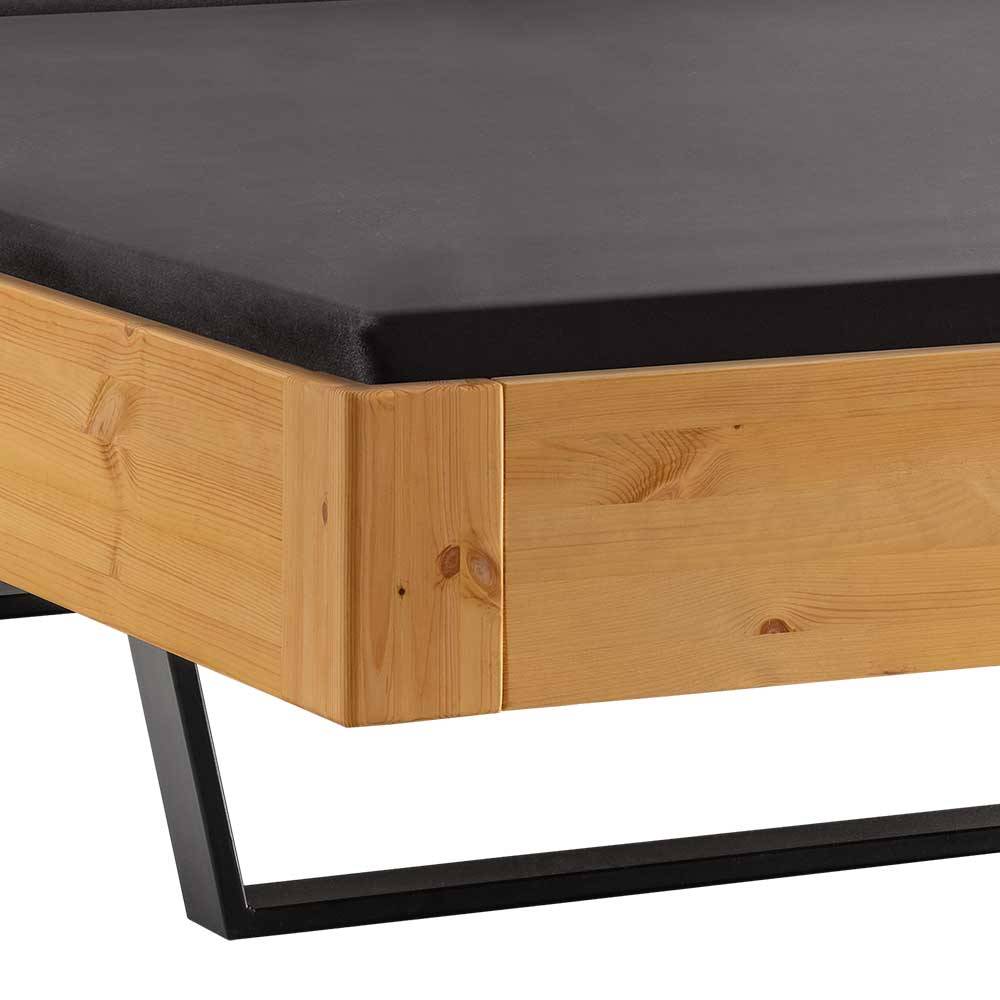 Bettrahmen aus hellem gelaugtem Kiefernholz mit stabilen schwarzen Metallfüßen am Fußende – Phiano