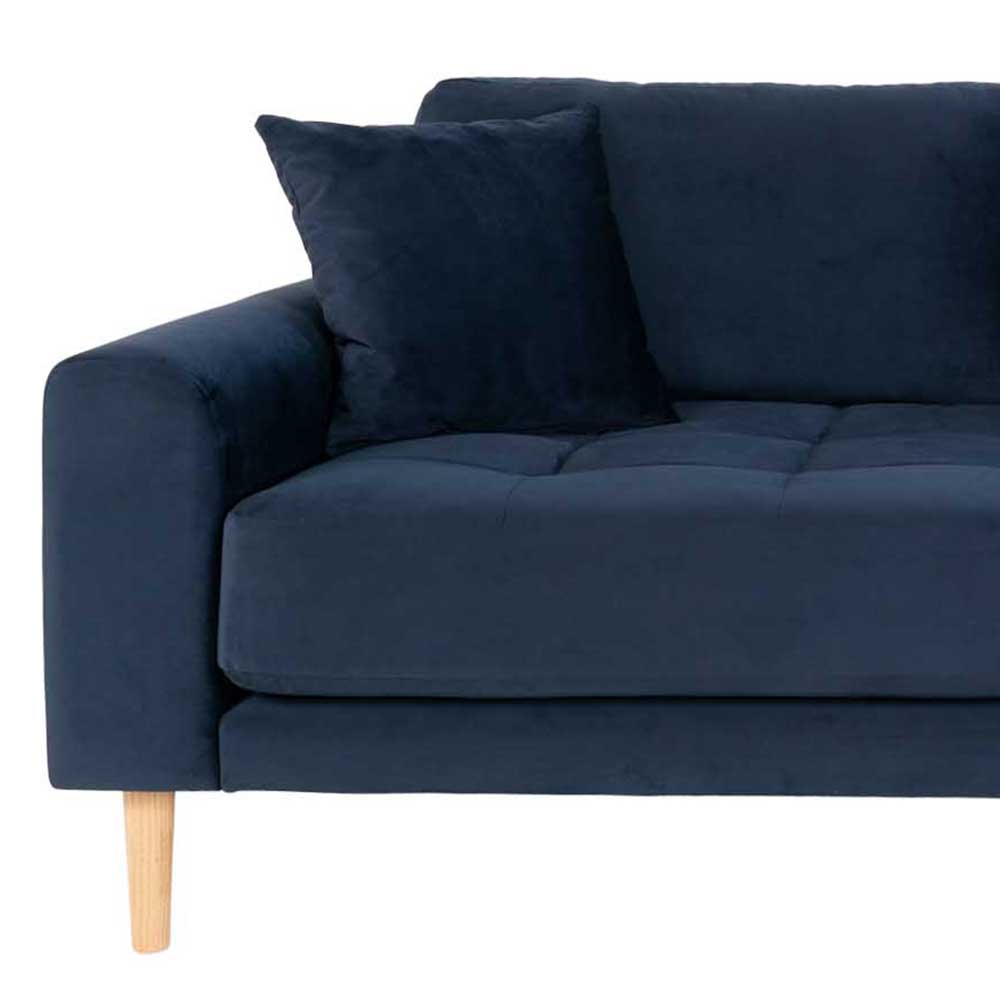 Linke Armlehne der blauen Samtcouch mit losem Kissen und hellen Holzbeinen – Jelleva
